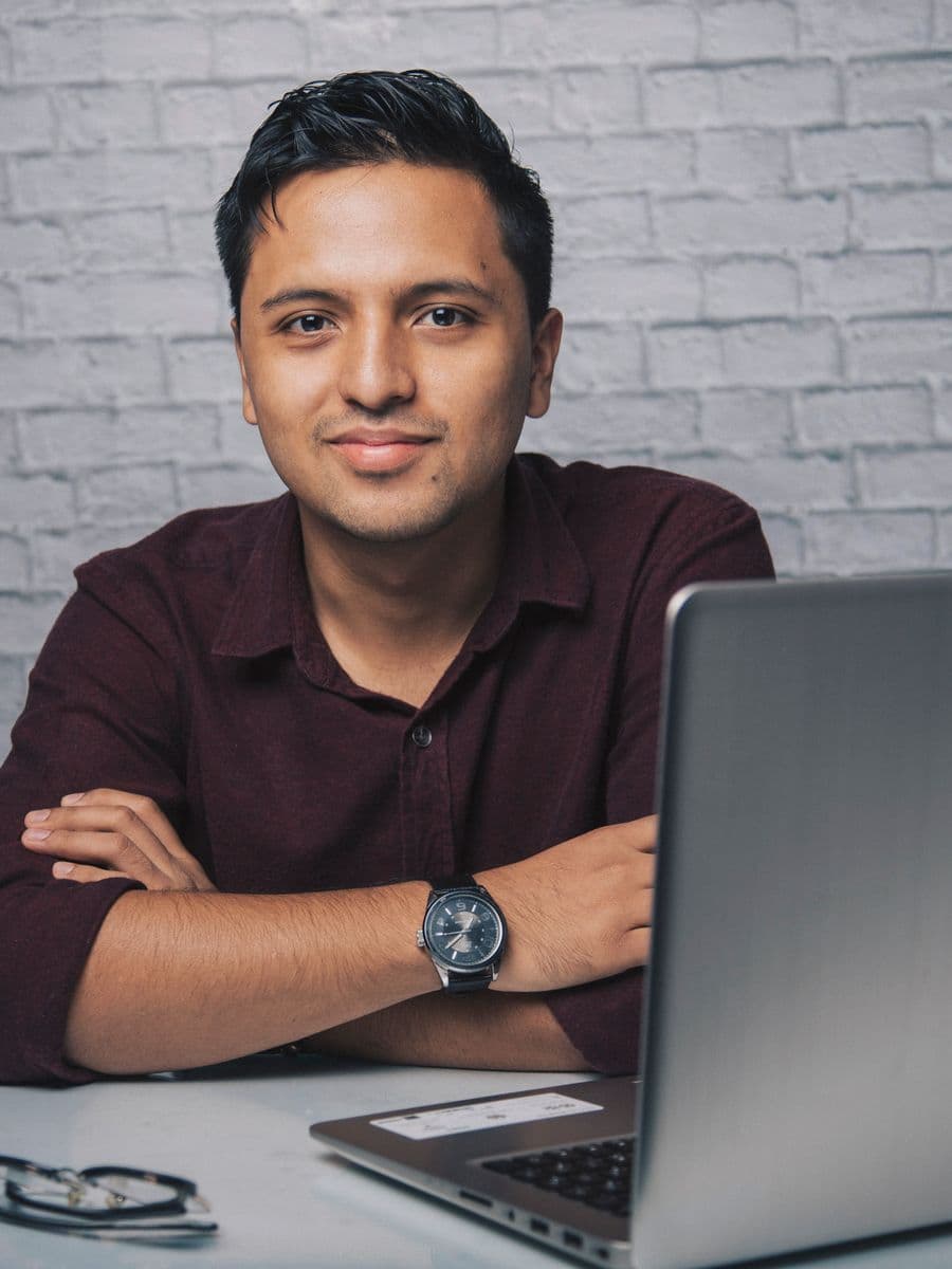 Consultant in glasses smiling while working on a laptop