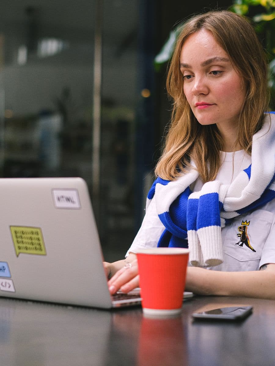 Freelance web developer working on a laptop at a cafe table