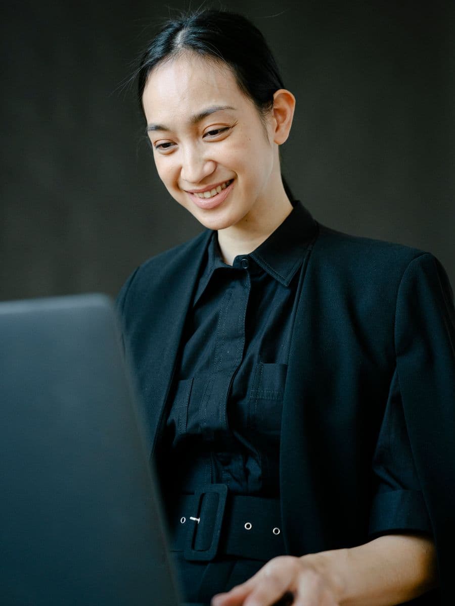 Marketer smiling while working on a laptop at her desk